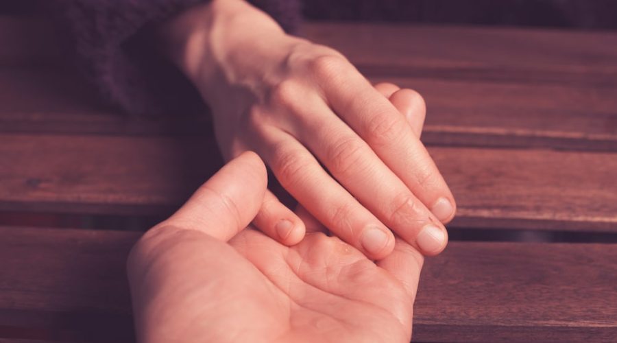 man reaching out over table and holding woman's hand