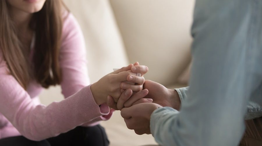 two people sitting opposite one another and holding hands