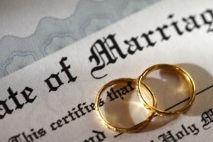 two wedding rings overlap on top of marriage certificate