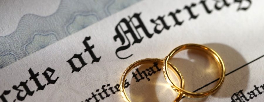 two wedding rings overlap on top of marriage certificate