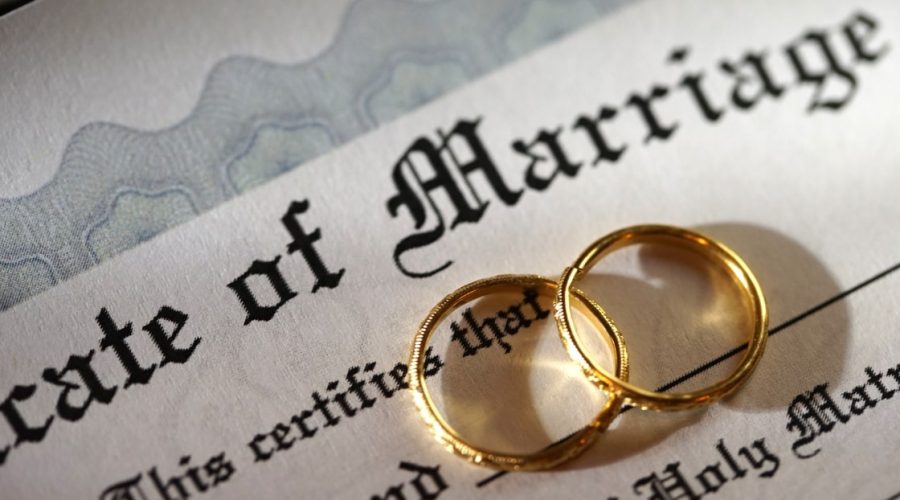 two wedding rings overlap on top of marriage certificate