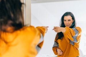 woman pointing at herself confidently in the mirror