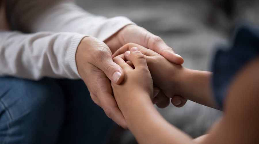 two people sitting opposite one another, man holding womans hands