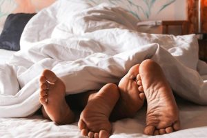 couples feet sticking out from under bed sheet