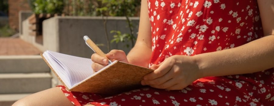 woman wearing red flower dress writing in journal