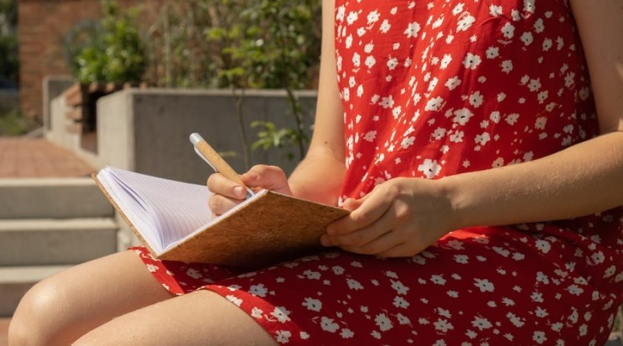 woman wearing red flower dress writing in journal