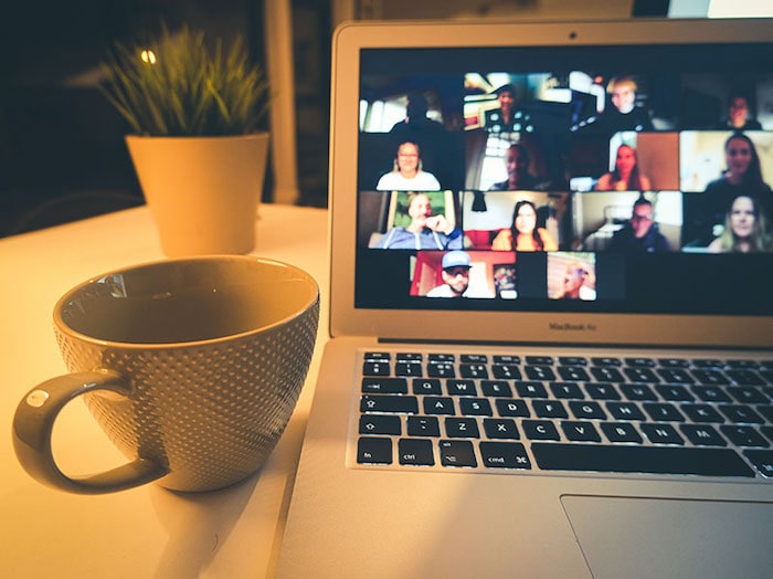 laptop showing group zoom call with coffee cup next to it