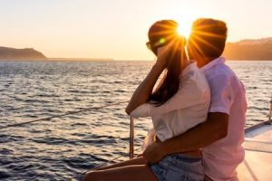 couple embracing on edge of boat at sunset