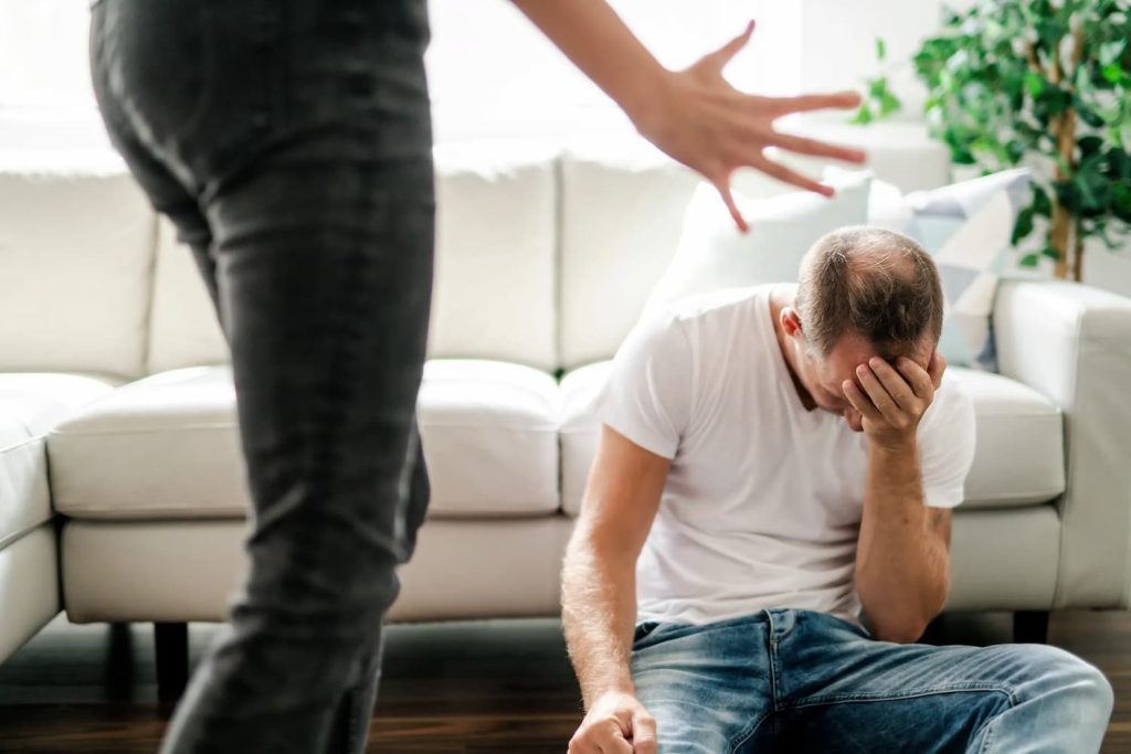 sad man sitting on the floor being berated by partner