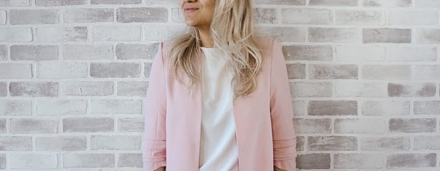 woman-in-pink-cardigan-and-white-shirt-leaning-on-the-wall