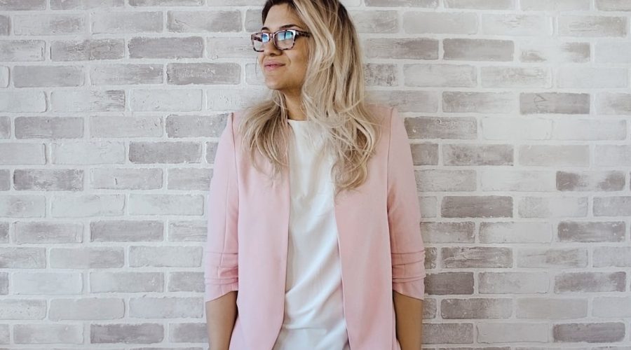 woman-in-pink-cardigan-and-white-shirt-leaning-on-the-wall